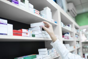 Closeup view of pharmacist hand taking medicine box from the shelf in drug store. Closeup view of pharmacist hand taking medicine box from the shelf in drug store.